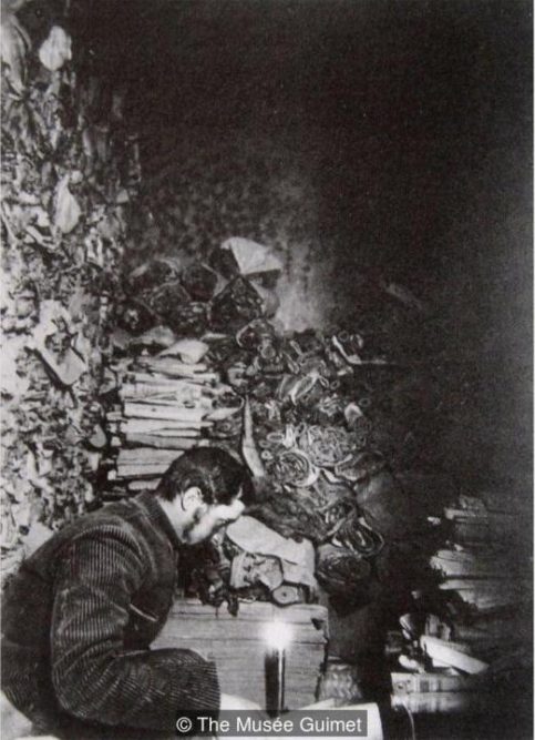 French sinologist Paul Pelliot in the Library Cave at Dunhuang in 1908 reading the manuscripts (Credit: The Musée Guimet)