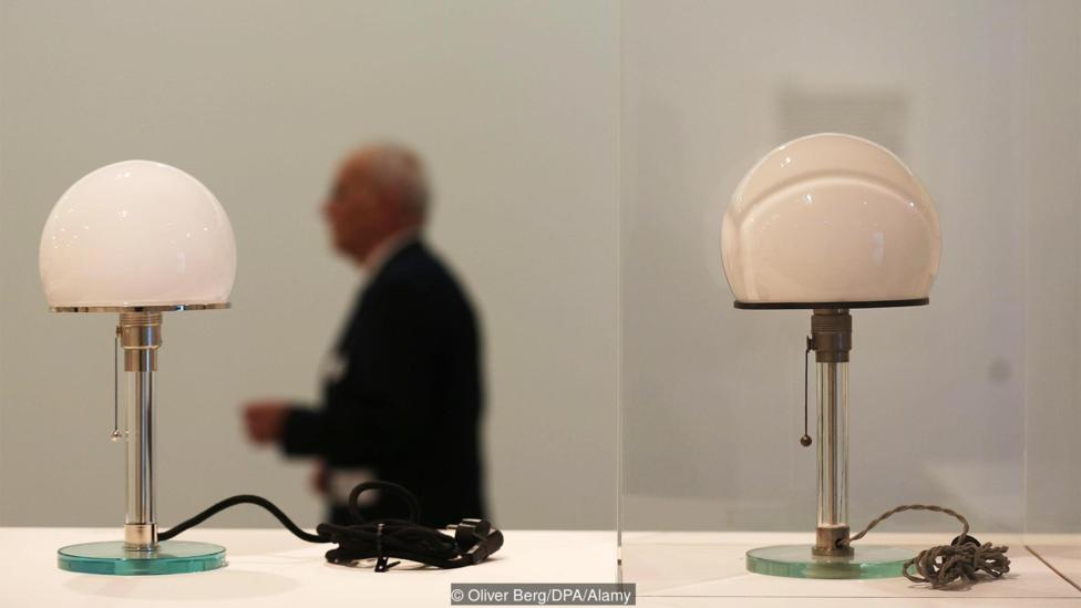 Bonn, Germany. 31st Mar, 2016. A man walks past an original desk lamp by Wilhelm Wagenfeld (R) and a replica (L) in Bonn, Germany, 31 March 2016. The exhibition ‘Das Bauhaus – Alles ist Design’ (lit. The Bauhaus – everything is design) will run at the Bun